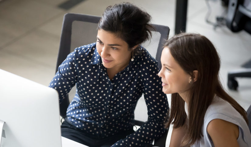 Multiracial colleagues sitting together looking at laptop screen in office Program and Policy Reviews