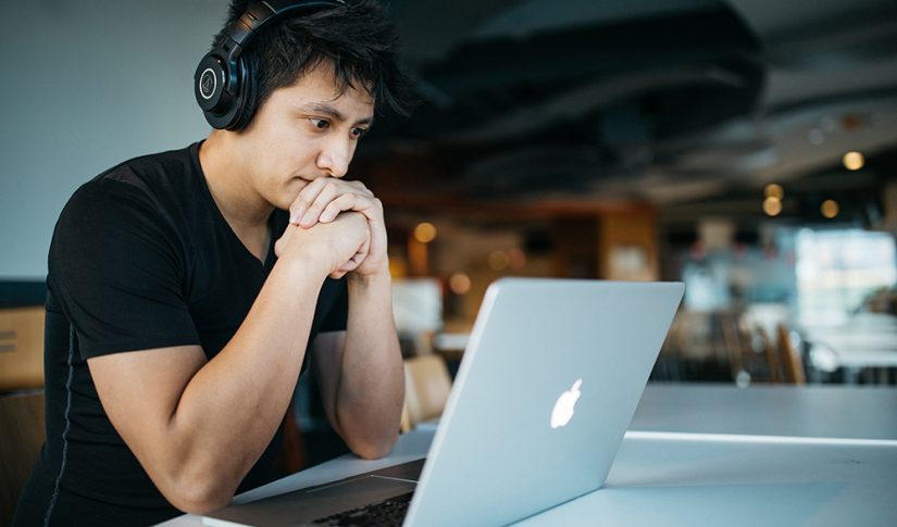 young man working in a café using headset and laptop Language Training
