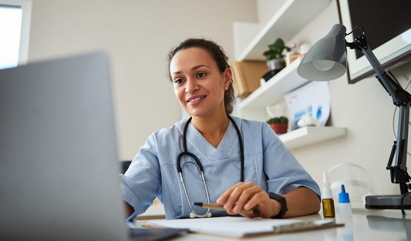 Woman watching a laptop screen while stretching her hand and typing on it Healthcare